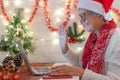 Portrait of old white-haired senior woman using laptop to video call with distant people. She celebrates the Christmas event Royalty Free Stock Photo