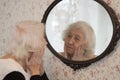 Portrait of old woman looking into a mirror at home Royalty Free Stock Photo