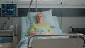 Portrait of old woman sitting in hospital ward bed to cure disease Royalty Free Stock Photo