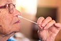 Portrait of old woman taking a self swabbing home tests Covid19 with antigen kit Royalty Free Stock Photo