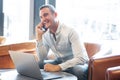 Older guy with laptop talking on mobile phone at cafe Royalty Free Stock Photo