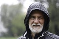 Portrait of an older white bearded man wearing a black hoodie on a rainy day with a blurry background Royalty Free Stock Photo