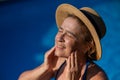 Portrait of an older woman applying sunscreen to her face while on vacation. Royalty Free Stock Photo