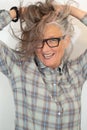 Portrait of an older woman, artist, in her fifties with grey hair and black glasses, her hands tearing her hair