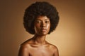 Portrait of one beautiful african american woman with an afro and flawless skin posing topless in a studio. Powerful Royalty Free Stock Photo