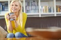 Portrait one beautiful woman sitting alone on the sofa in her living room, smiling and drinking coffee. Young woman Royalty Free Stock Photo