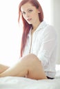 Portrait of one beautiful young redhead woman relaxing on a bed at home. Confident female feeling flirty, sensual and