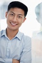 Portrait of one confident young asian business man standing with arms crossed against a glass wall in an office. Happy Royalty Free Stock Photo