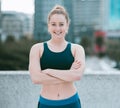 Portrait of one confident young caucasian woman standing with arms crossed ready for exercise outdoors. Determined