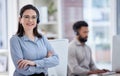 Portrait of one confident young caucasian woman standing with arms crossed while working in a call centre with her Royalty Free Stock Photo