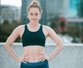 Portrait of one confident young caucasian woman standing with hands on hips ready for exercise outdoors. Determined