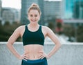 Portrait of one confident young caucasian woman standing with hands on hips ready for exercise outdoors. Determined