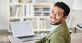 Portrait of one confident young mixed race businessman working on laptop at desk in an office. Ambitious motivated