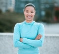 Portrait of one confident young mixed race woman standing with arms crossed ready for exercise outdoors. Determined