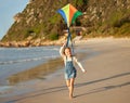 Portrait of one cute little caucasian girl running alone on the beach sand while holding her kite on a sunny summer day Royalty Free Stock Photo