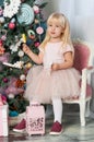 Portrait of one little Caucasian cute blonde girl with colored lollipops in the festive New year studio room Royalty Free Stock Photo