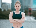 Portrait of one serious young caucasian woman standing with arms crossed ready for exercise outdoors. Determined female