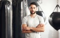 Portrait of one serious young hispanic man standing with his arms crossed ready for exercise in a gym. Muscular mixed