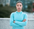 Portrait of one serious young mixed race woman standing with arms crossed ready for exercise outdoors. Determined female
