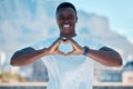 Portrait of one smiling muscular african american man outside alone and using hand gestures to make a heart shape sign Royalty Free Stock Photo