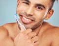 Portrait of one smiling young indian man brushing his teeth against a blue studio background. Handsome guy grooming and Royalty Free Stock Photo