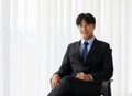 Portrait one young asian businessman wearing suit sitting chair while feel confident with smiling as smile on face looking at Royalty Free Stock Photo