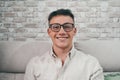 Portrait of one young attractive man looking at the camera smiling and having fun sitting on the sofa. Happy male teenager wearing Royalty Free Stock Photo