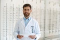 Portrait of ophthalmologist offering glasses to client in front of showcase in optics store