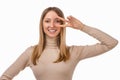 Portrait of optimistic blond girl showing peace sign over eye and smiling, white background. Just be cool about it