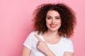 Portrait of optimistic girl with wavy hairstyle wear white t-shirt indicating at discount empty space isolated on pink Royalty Free Stock Photo