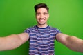 Portrait of optimistic handsome cheerful man with bristle wear stylish t-shirt making selfie smiling isolated on green Royalty Free Stock Photo