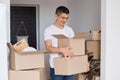 Portrait of optimistic handsome man wearing white T-shirt standing with cardboard boxes with personal stuff, looking inside with Royalty Free Stock Photo