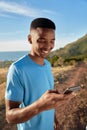 Portrait orientation of Black young Adult male checking his phone while on a run in the beautiful mountains