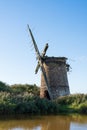 A portrait orientation picture of the remains of Brograve mill in North Norfolk, UK on a blue sky day