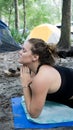 Portrait ot of a young woman with namaste prayer pose hands toguether yoga while camping in the forest