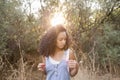 Portrait outdoors of a beautiful young afro american woman at sunset. Green background. Lifestyle. Wearing jeans casual summer Royalty Free Stock Photo