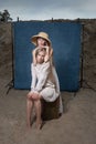 Portrait outdoors on sand in front of blue background, cute young pretty twins