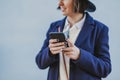 portrait outdoors of a young beautiful woman with stylish clothes posing with a modern hat and using mobile phone. lifestyle Royalty Free Stock Photo