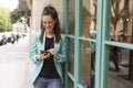 Portrait outdoors of young happy blogger woman with mobile phone. Glass windows background. Wearing casual clothes. Fun and Royalty Free Stock Photo