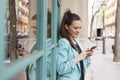 Portrait outdoors of young happy blogger woman with mobile phone. Glass windows background. Wearing casual clothes. Fun and Royalty Free Stock Photo