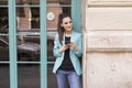 Portrait outdoors of young happy blogger woman with mobile phone. Glass windows background. Wearing casual clothes. Fun and Royalty Free Stock Photo