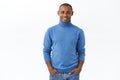 Portrait of outgoing good-looking african american guy with bristle, blue turtleneck, hold hands in jeans pockets