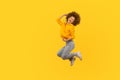 Portrait of overjoyed enthusiastic curly-haired girl in urban style hoodie and jeans jumping high in air Royalty Free Stock Photo