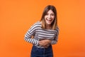 Portrait of overjoyed excited adorable young woman with brown hair in long sleeve striped shirt. indoor studio shot isolated on Royalty Free Stock Photo