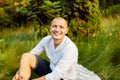 Portrait of overjoyed smiling man sitting on blanket in park