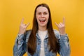 Portrait of overjoyed young woman showing rock and roll hand sign, screaming and gesturing to heavy metal, rock music, wearing Royalty Free Stock Photo