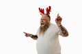 Isolated portrait on a white background of an overweigh man with tattooed arms wearing a hoop with antlers on the head expressing