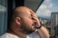 Portrait of overweight man has headache touching forehead in heat summer weather.