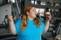 Portrait of overweight woman holding dumbbell looking with irresistible desire at donut
