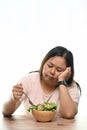 Portrait of overweight woman is tired of diet restrictions eating green salad.